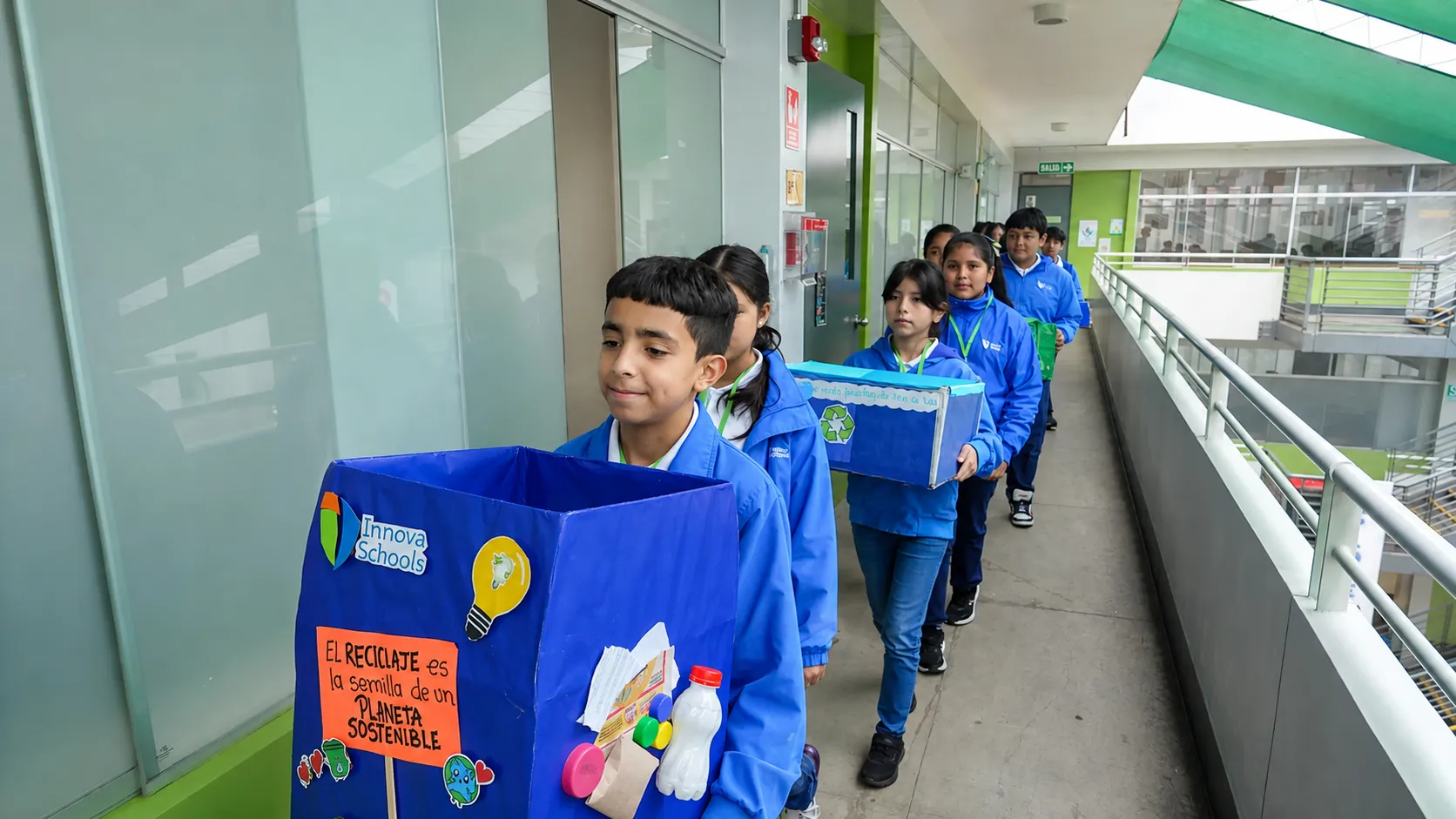 Niños recogiendo cajas de reciclaje llevándolas con orgullo a otros salones.