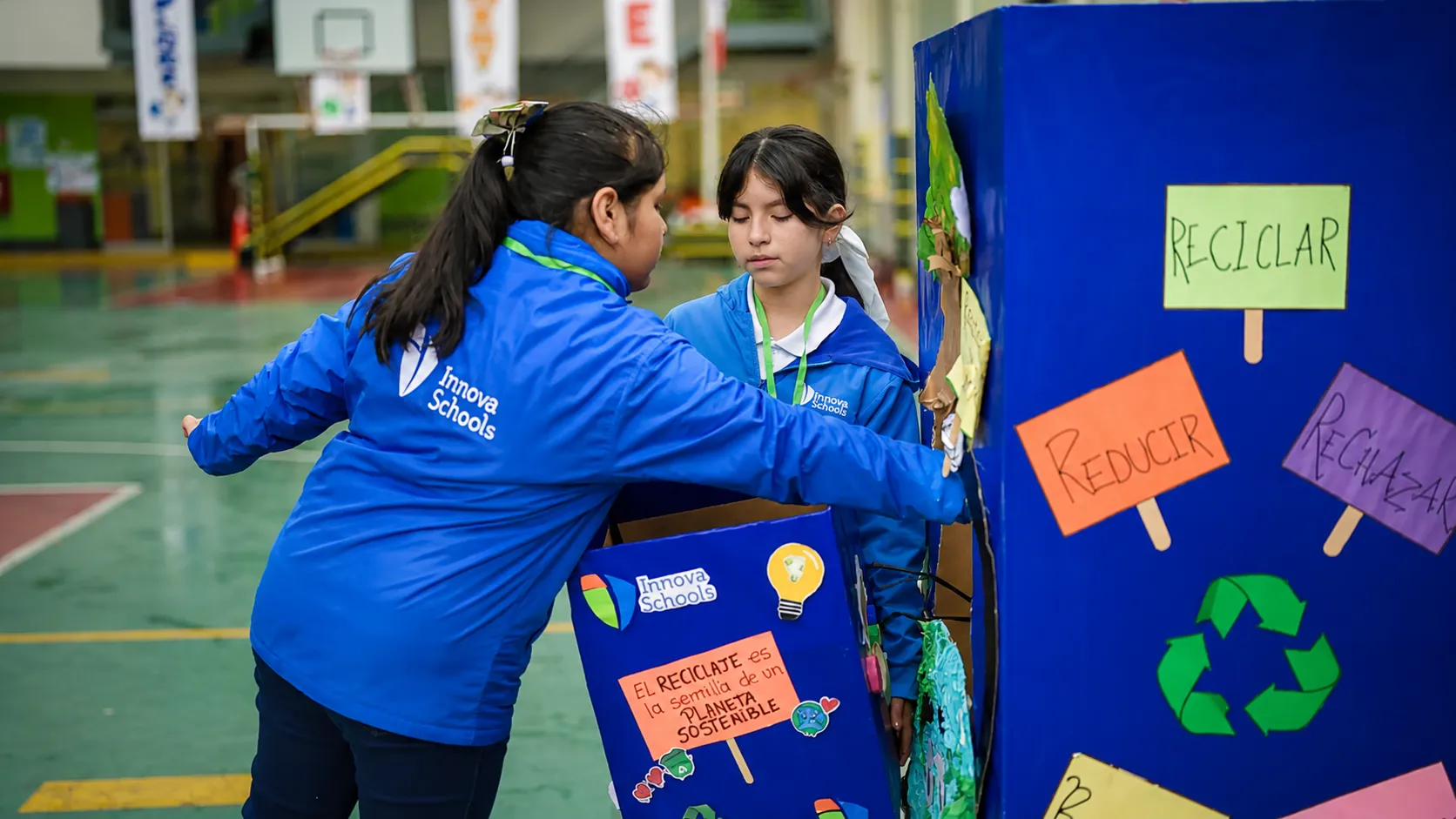 Niñas impulsando el reciclaje en el colegio alegremente.